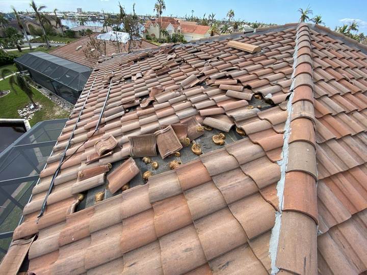 Hurricane-damaged tile roof with broken and displaced tiles